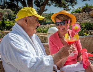 Et eldre par som tar en skål og nyter drinker i solen.